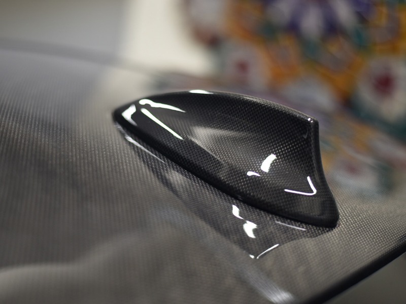 Close-up image of a black carbon fiber 'shark fin' antenna cover on a vehicle.