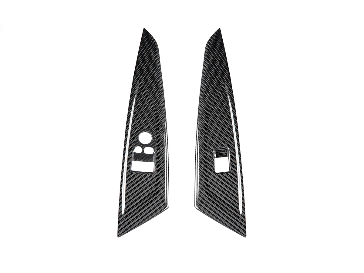 A set of two black dry carbon window switch panel trims designed for a BMW vehicle.