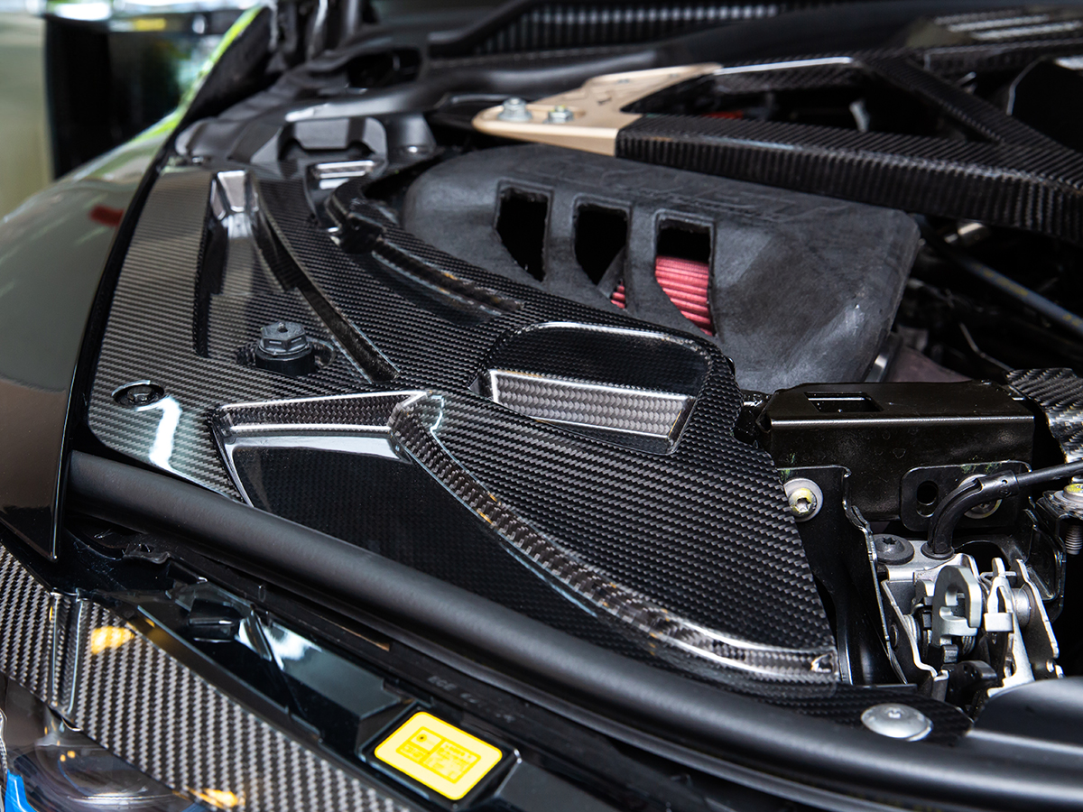 AutoTecknic Dry Carbon V2 Engine Bay Trim installed in the engine compartment of a car, showcasing the carbon fiber texture and black color.