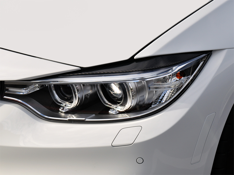 Close-up of a car's carbon fiber headlight trim with a sleek design.