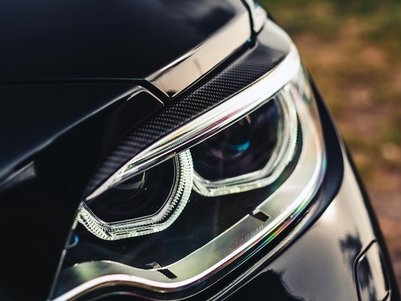 Close-up of a car's carbon fiber headlight trim with a focus on the sleek design and texture.