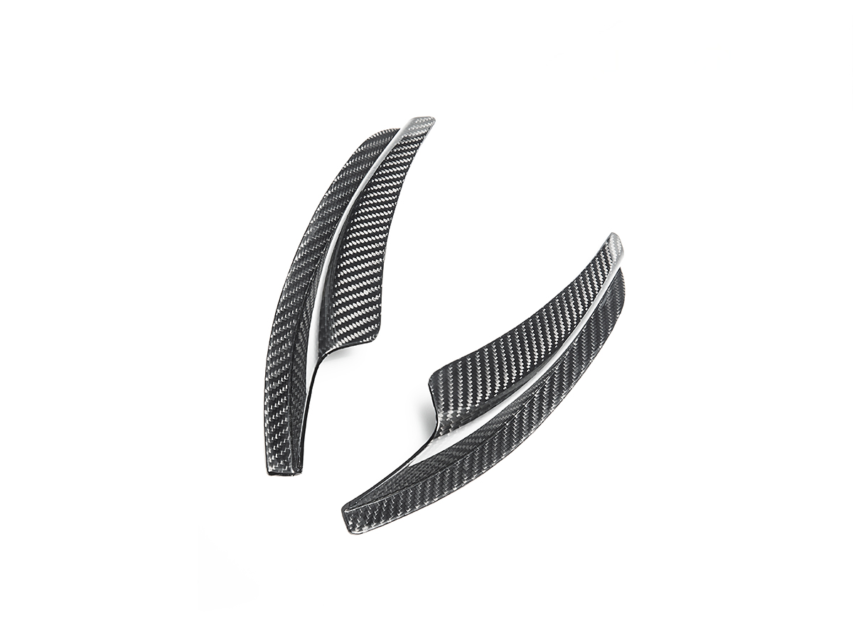 A set of two black dry carbon fiber bumper canards for a BMW, displayed against a white background.
