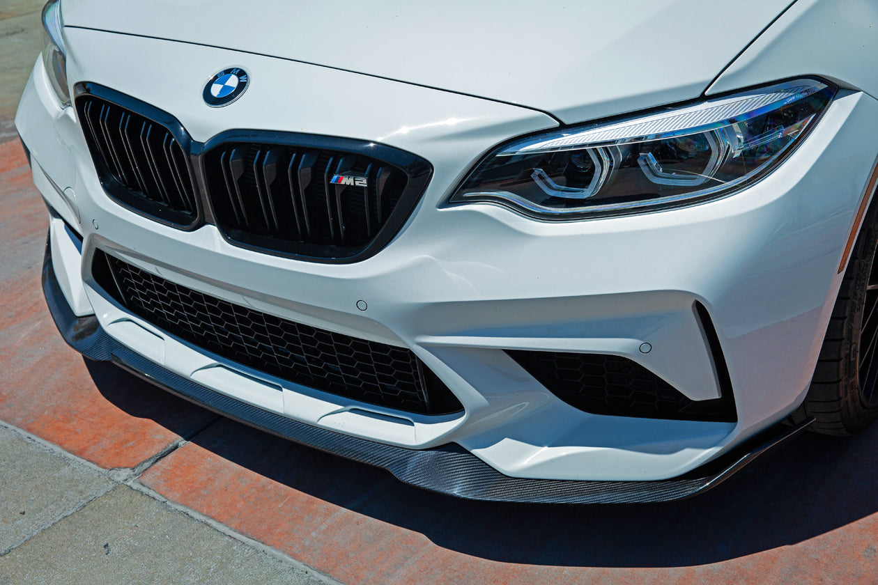 Close-up of a white BMW car featuring the AutoTecknic Carbon Competition Front Aero Lip installed on the front bumper.