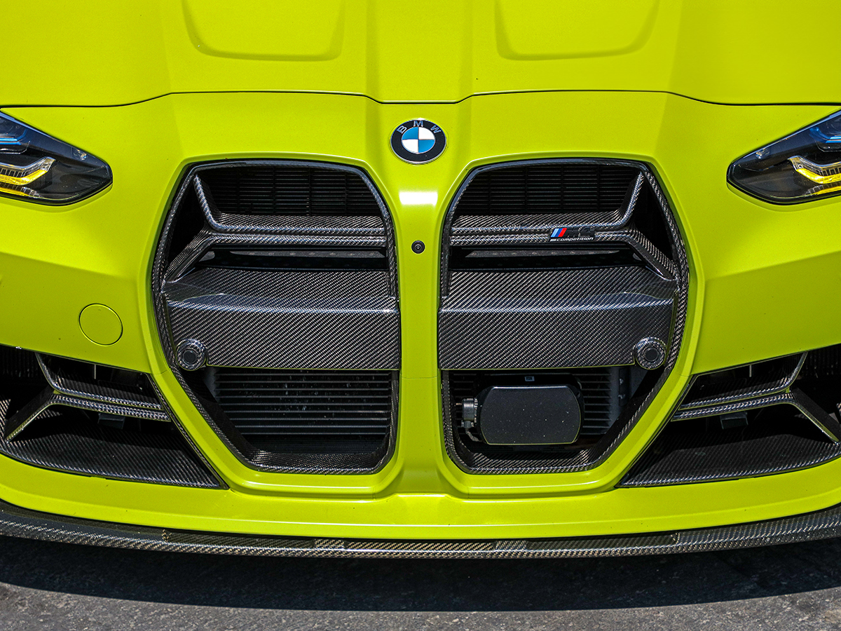 Close-up of the front grille of a BMW vehicle featuring a dry carbon fiber texture.