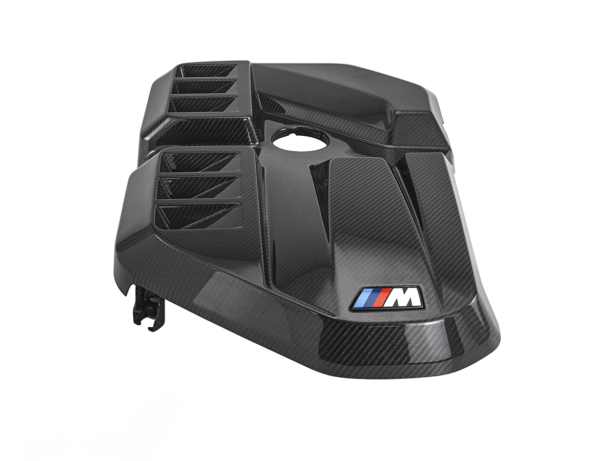 AutoTecknic dry carbon fiber engine cover for a G87 M2, showcasing a black textured pattern with the BMW M emblem.