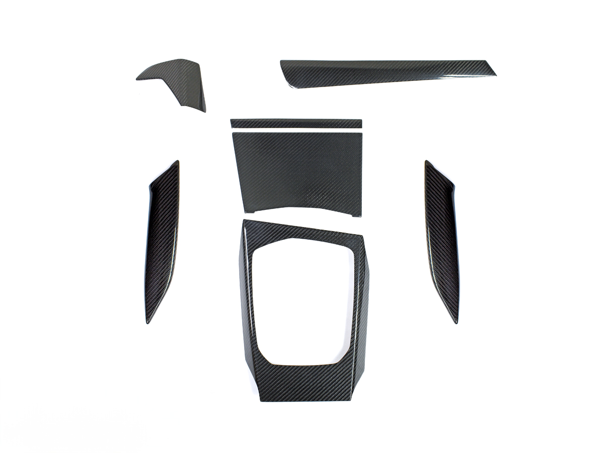 A set of dry carbon fiber interior trim pieces for BMW models, including door panels and air vent trims.