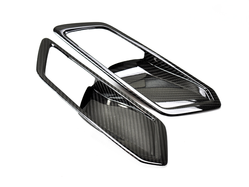 A set of dry carbon interior door handle trim for a BMW, featuring a high gloss clear coat finish.