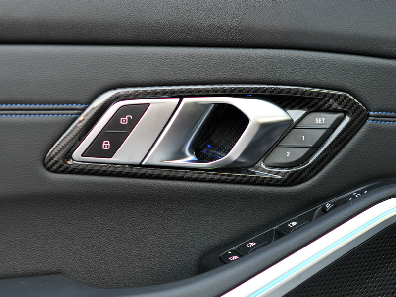 An image showing the AutoTecknic Dry Carbon Interior Door Handle Trim Set installed on a vehicle's interior door panel.