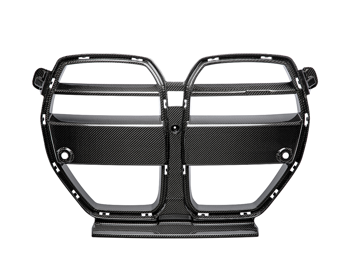 A black AutoTecknic dry carbon motorsport front grille for BMW G80 M3 and G82/ G83 M4 models.