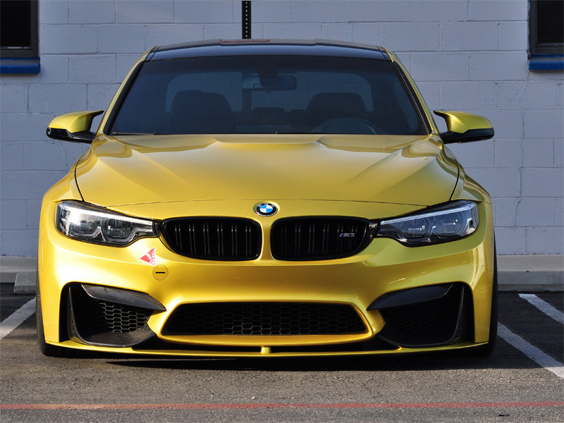 Yellow BMW car with AutoTecknic dry carbon performance bumper trim installed.