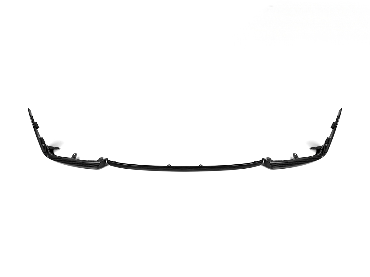 A black AutoTecknic dry carbon performante front lip designed for the G87 M2, featuring a sleek and sophisticated aerodynamic shape.