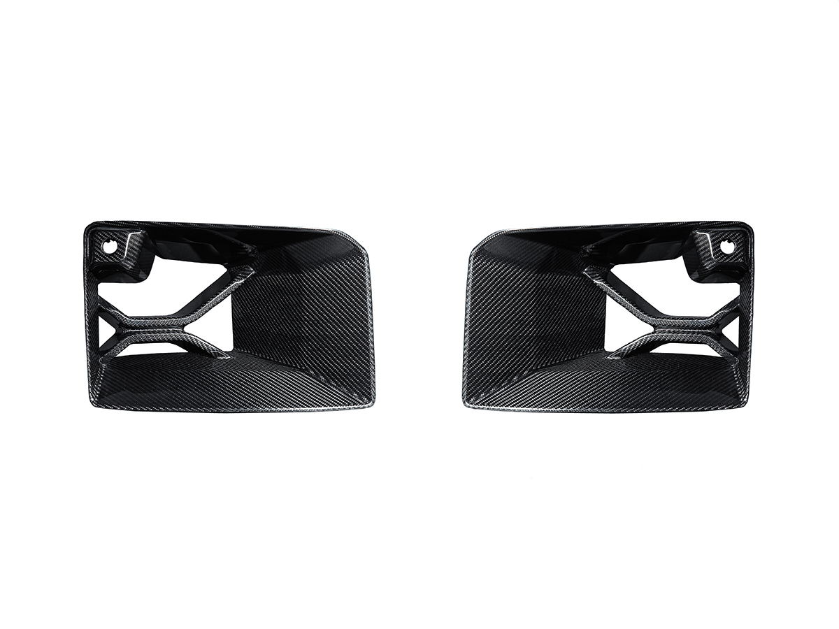 A set of two black carbon fiber front bumper lower vent trim pieces for a BMW G87 M2.