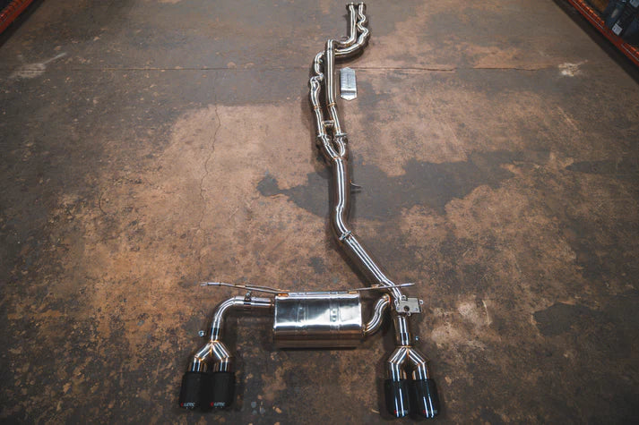 A valved sport exhaust system for BMW M2 Competition, displayed on a floor, consisting of stainless steel pipes and components.