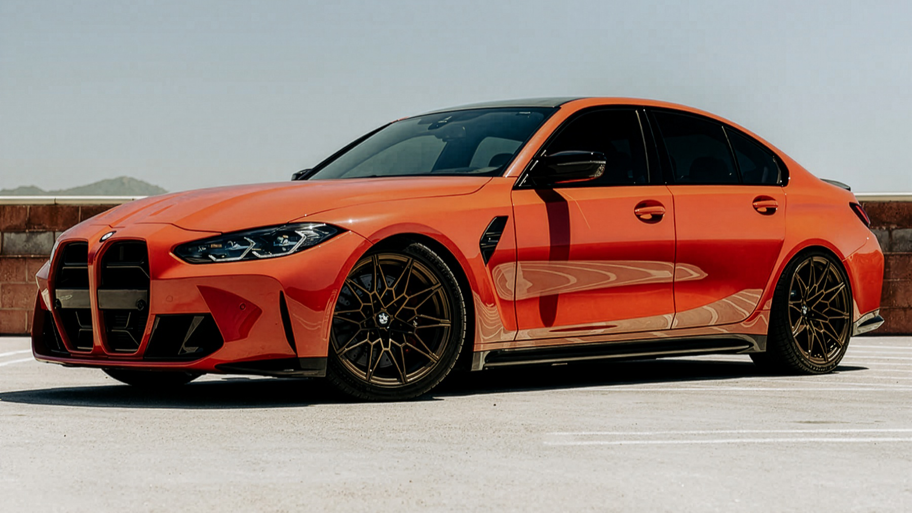 Orange BMW car on a clear road with a light blue sky