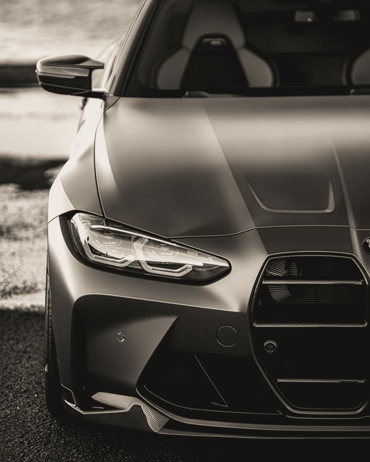 Close-up of a car's front grille and headlight on a road