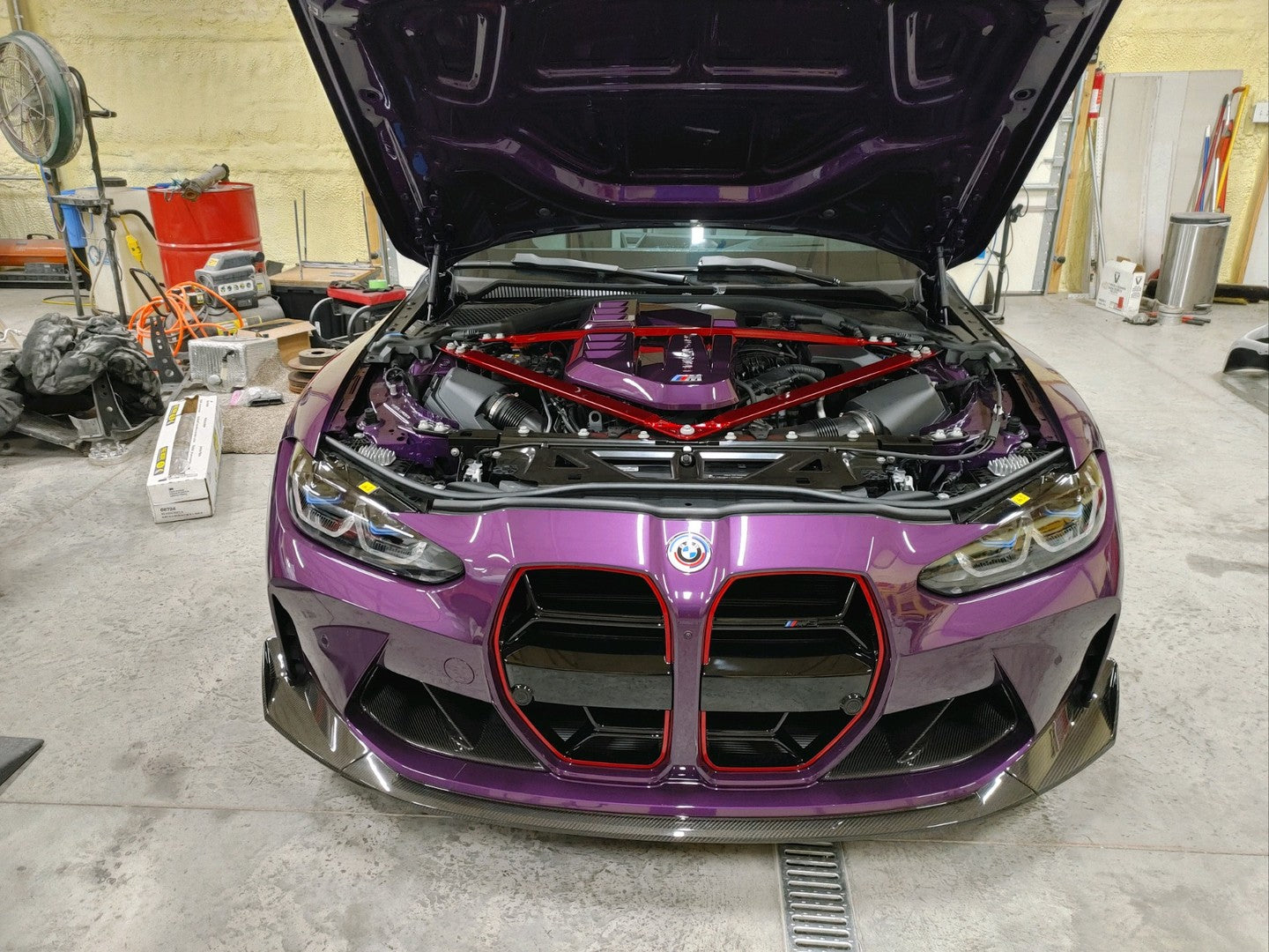 Purple BMW car with open hood in a garage setting