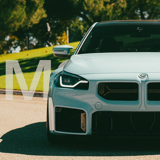 Light blue BMW car on a road with greenery in the background